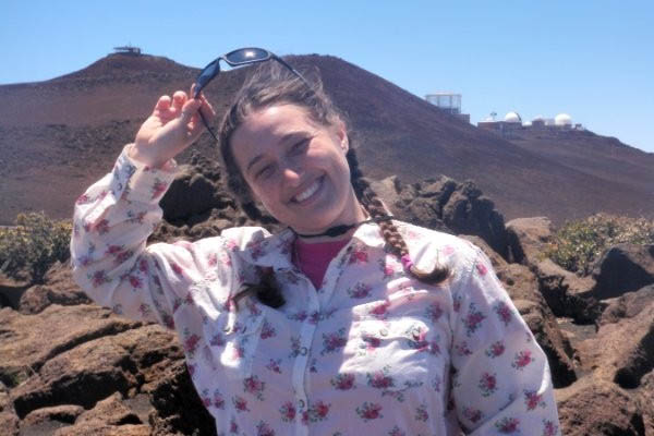 Professor Tina Wasem smiling with basaltic rocks immediately behind her.