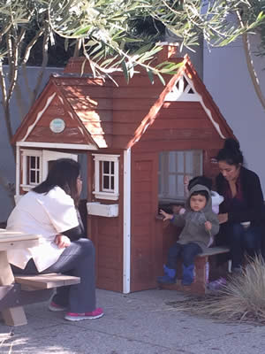 Child and teacher in front of play house.