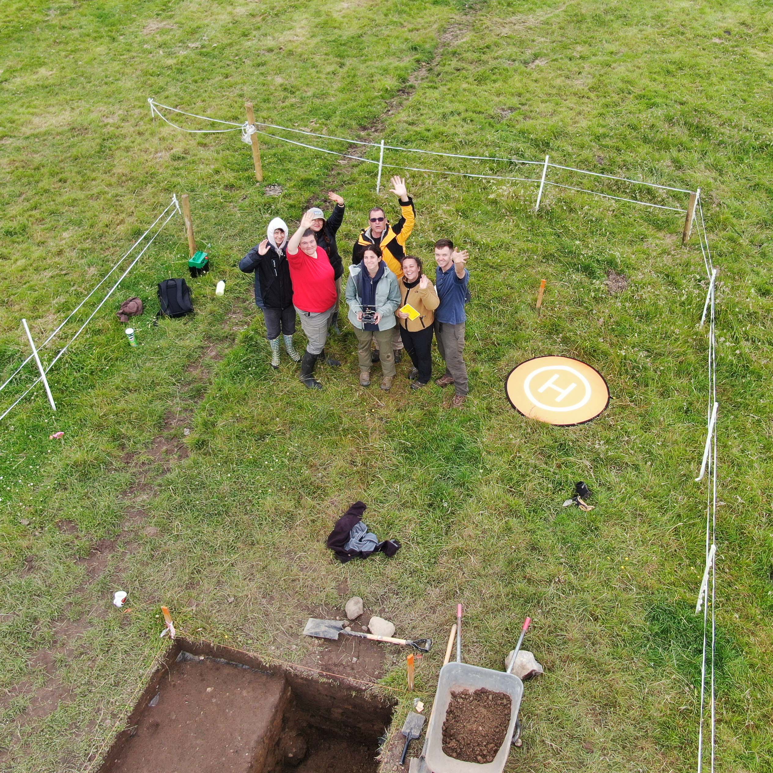 Archaeology team using a drone to take an image of themselves near a test unit