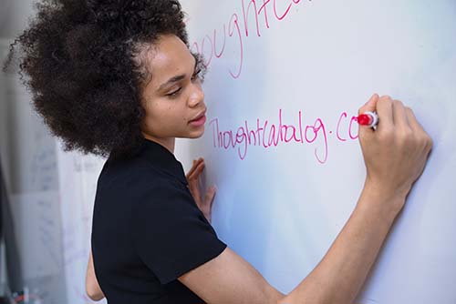 A young woman writing on a whiteboad